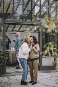 Happy female senior friends greeting each other at dinner party in backyard