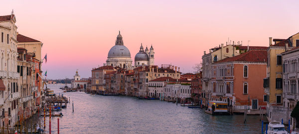 Canal amidst buildings against sky during sunset