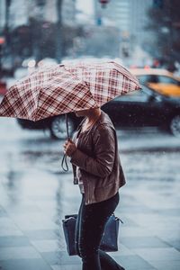 Woman with umbrella walking on wet street