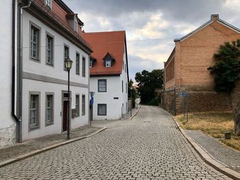 Empty road amidst buildings against sky