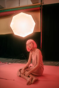 Young woman sitting in illuminated room