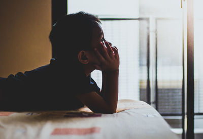 Portrait of a young woman sitting on bed at home