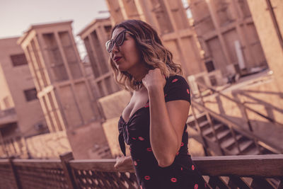 Close-up of young woman wearing sunglasses while standing by railing