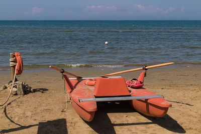 Deck chairs on shore at beach against sky