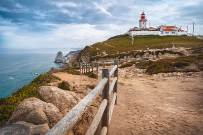 Lighthouse by sea against sky