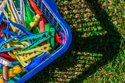 High angle view of multi colored clothespins in basket on grass