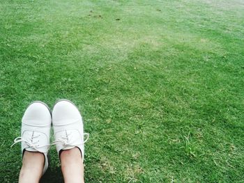 Low section of woman sitting on grassy field