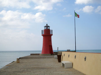 Lighthouse by sea against sky