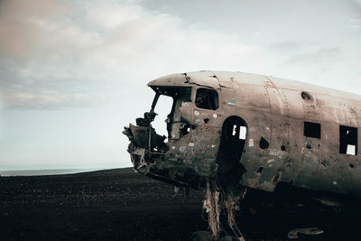 Abandoned airplane on beach against sky