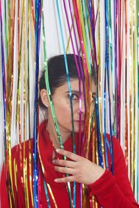Portrait of young man holding multi colored curtain
