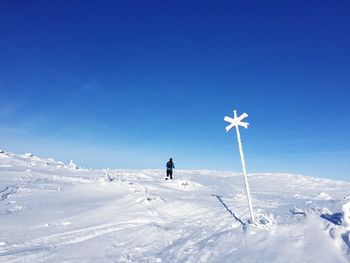Man on snow covered landscape against blue sky