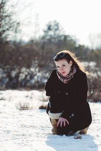 Young woman sitting on snow covered land