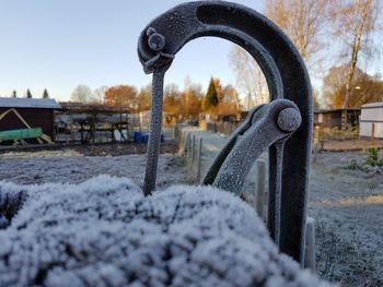 Close-up of snow covered metal against sky