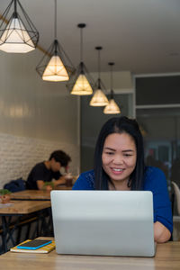 Portrait of woman using smart phone while sitting on table
