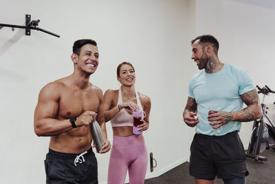 Cheerful sports people drinking water while standing at gym