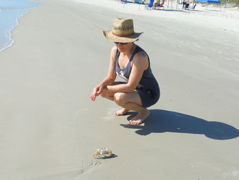 Woman watching crab on beach