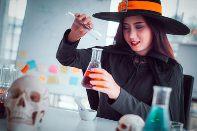 Portrait of young woman holding drink at table