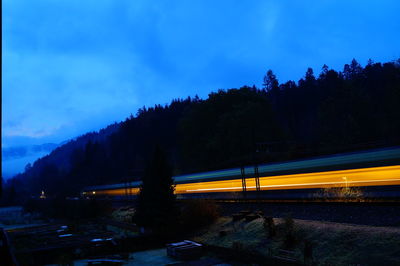 Cars on illuminated bridge against sky at dusk