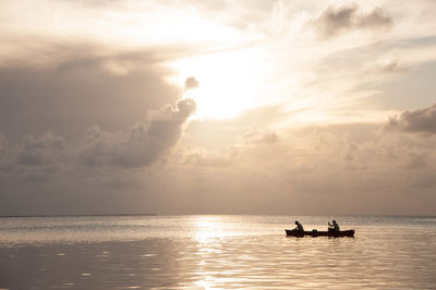 Boat sailing in sea at sunset