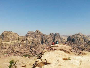 Rear view of people sitting on rock formation at petra