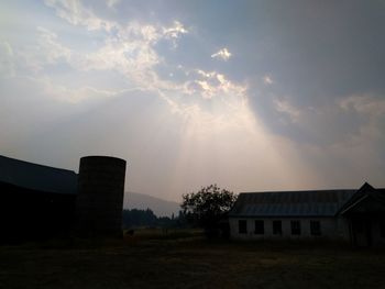 Buildings on field against sky at sunset