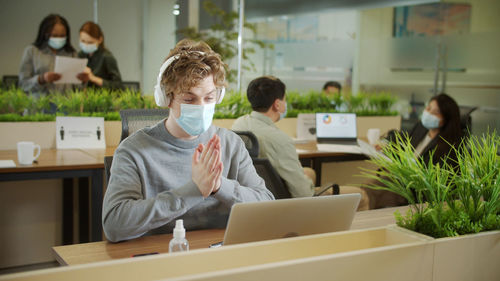 Businessman wearing mask talking on video call at office