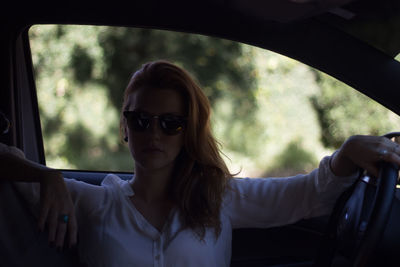 Young woman wearing sunglasses while sitting in car
