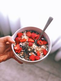 Cropped hand of woman holding breakfast in bowl at home