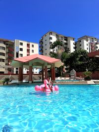 People in swimming pool against buildings