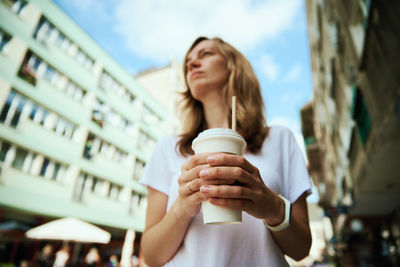 Woman holds paper coffee cup at city street