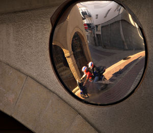 Reflection of people riding motorcycle on road mirror