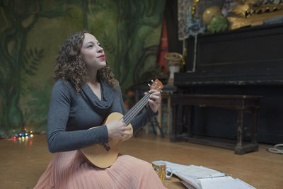 Young female musician practicing the ukulele