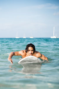 Full length of shirtless man swimming in sea against sky