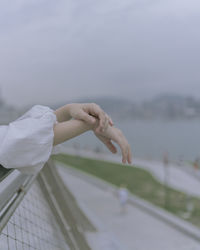 Close-up of young woman hand on the railing against sky in city