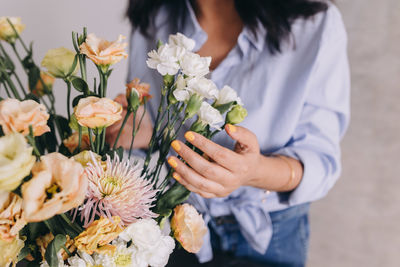 Midsection of woman holding bouquet of roses and carnations 