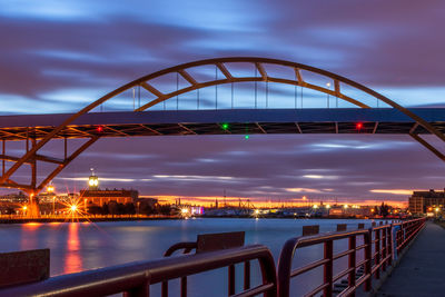 Bridge over river in city against sky