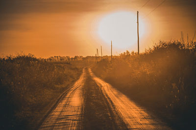 Road amidst trees against sky during sunset