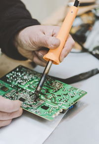 Cropped hands of engineer repairing mother board on table