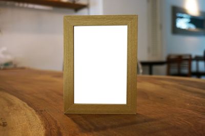 Close-up of blank picture frame on wooden table