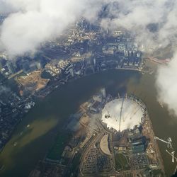 Aerial view of city by lake against clouds