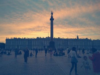 People at palace square against orange sky