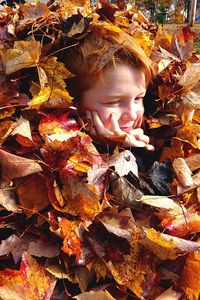 Close-up of boy amidst autumn leaves