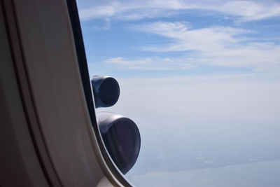 Airplane flying against sky seen through window