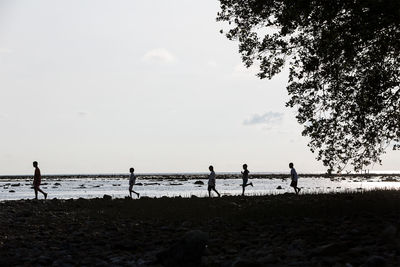 People standing on beach against sky