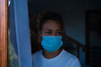 Close-up of woman wearing mask seen through window