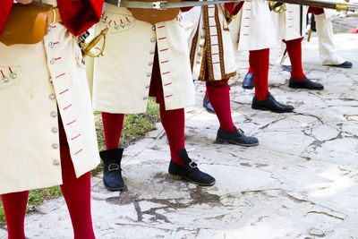 People in costume with weapons standing on footpath