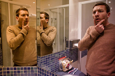 Shocked man standing by mirror in bathroom