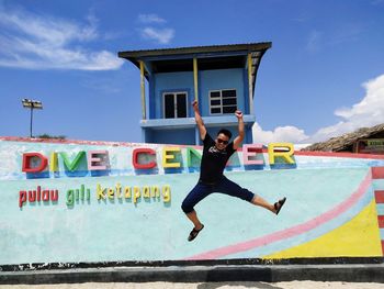 Full length of man jumping against wall