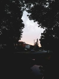 Silhouette of city street against sky during sunset