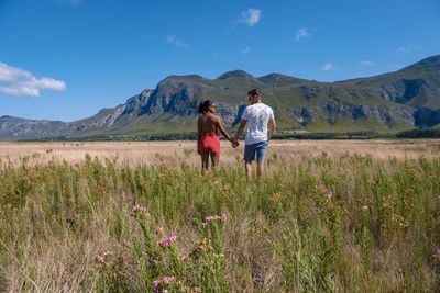 Rear view of woman walking on field against mountain